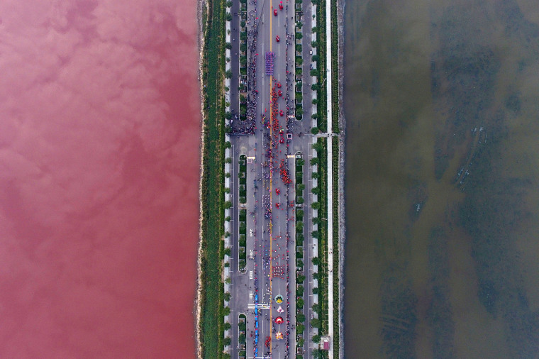 Image: A salt lake which is separated by a road, shows parts of it in different colours due to algae, in Yuncheng, Shanxi Province, China
