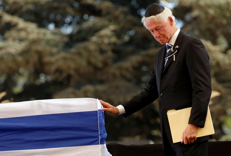 Image: Former US President Bill Clinton stands in front of the flag-draped coffin of the former Israeli President Shimon Peres