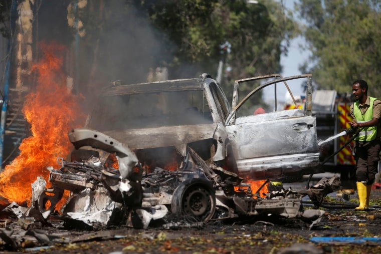 Image: A firefighter tries to extinguish the fire from the wreckage of a burning vehicle after it exploded in front of the Blue Sky restaurant in Mogadishu, Somalia