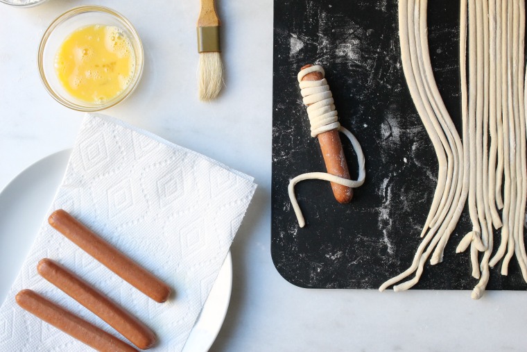 Roll hot dogs in pastry dough strips to form mummies