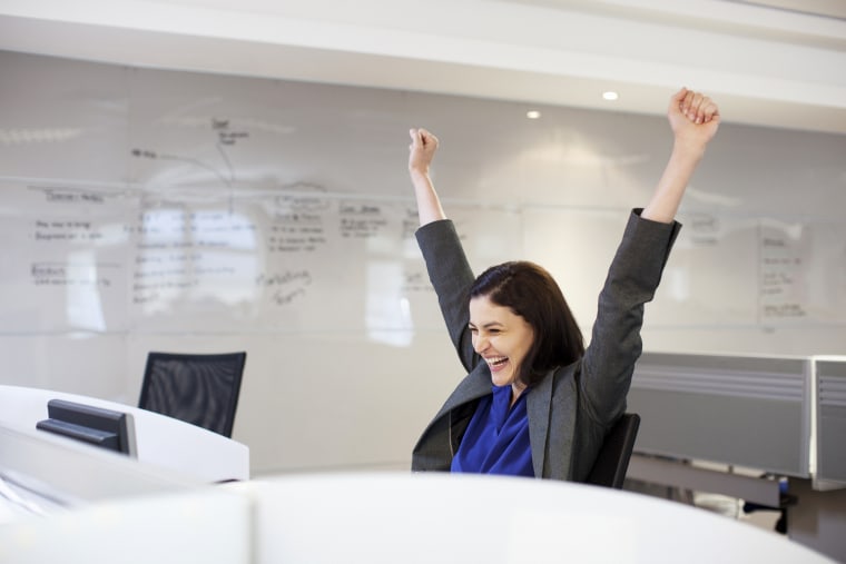 Enthusiastic businesswoman with arms raised in office