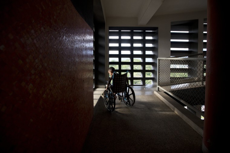 In this Sept. 19, 2016 photo, Marvin Osuna sits near a sunlit window in a passageway at University Hospital, in Caracas, Venezuela.
