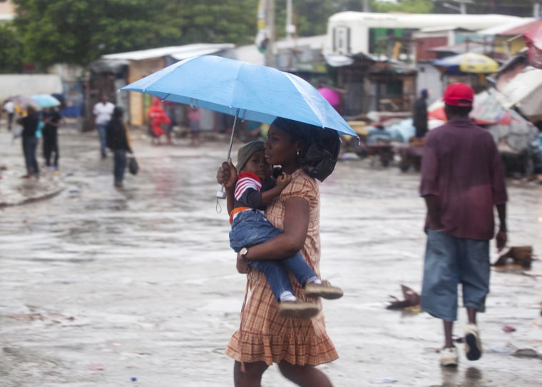 Image: A woman carrying a child walks in the rain triggered by Hurricane Matthew