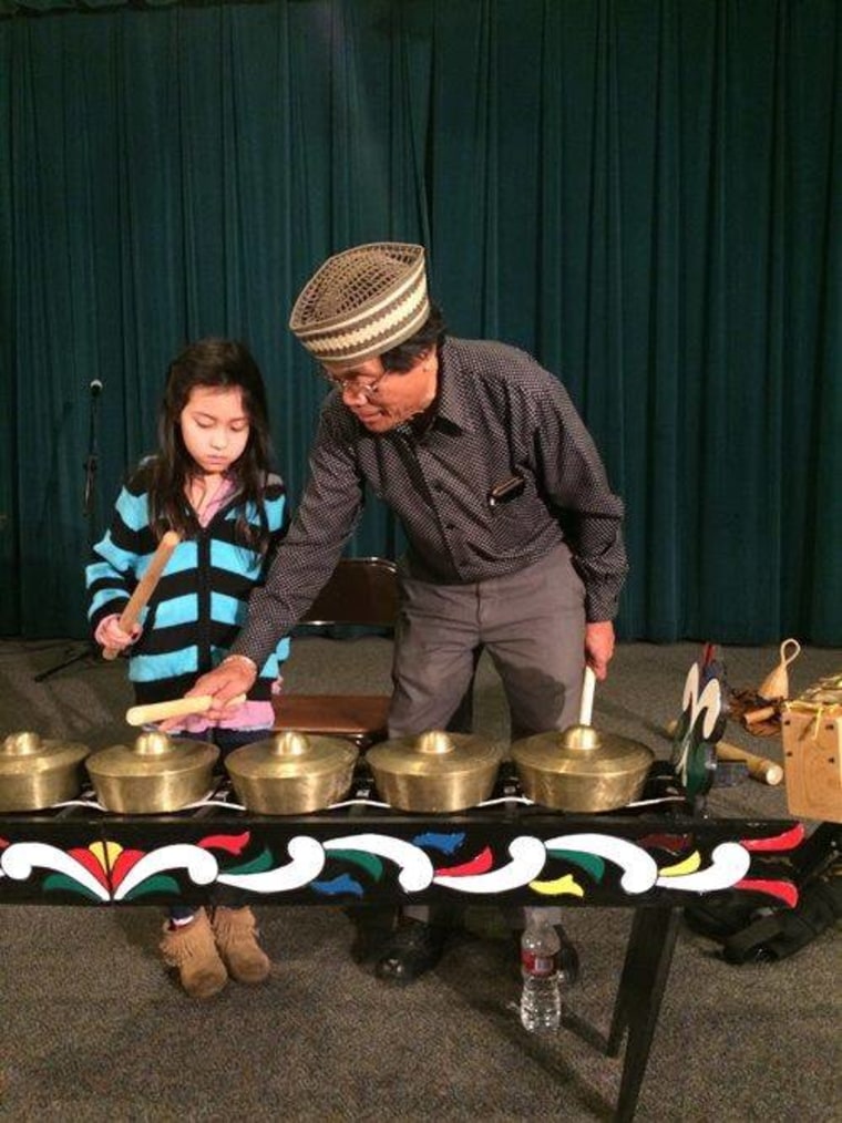 Kalanduyang teaching a child how to play the kulintang gongs during a demonstration.