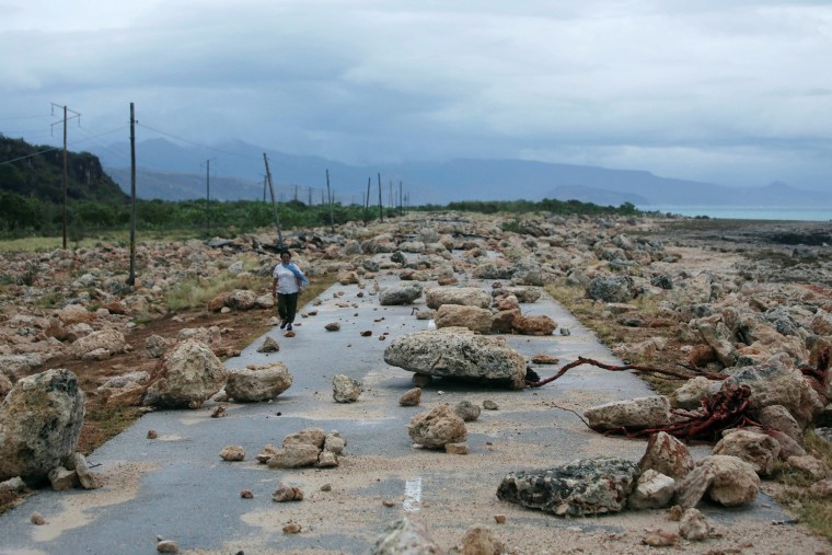 Image: A woman walks on a highway blocked by rocks after the passage of hurricane Matthew on the coast of Guantanamo province