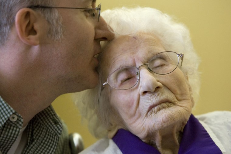 Image: Besse Cooper, 114, right, receives a kiss from her grandson