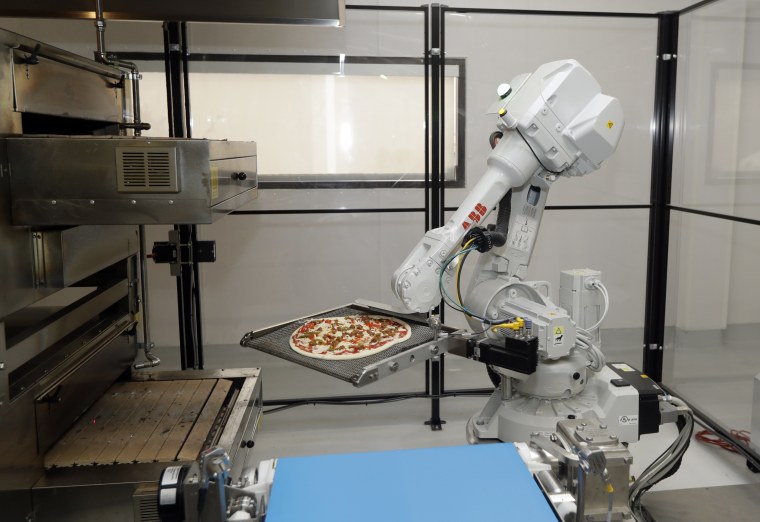 Image: A robot places a pizza into an oven at Zume Pizza