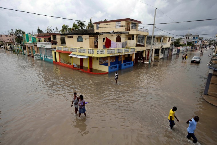 Image: People walk in a flooded area after Hurricane Matthew in Les Cayes