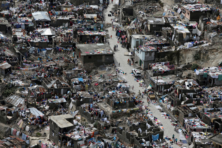 Image: People walk on a street next to destroyed houses after Hurricane Matthew hit Jeremie