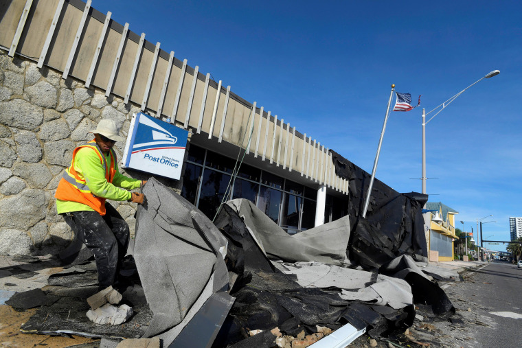 Image: Jordan Mays removes the roof that blew off of a U.S. Post Office location in the aftermath of Hurricane Matthew in Daytona Beach