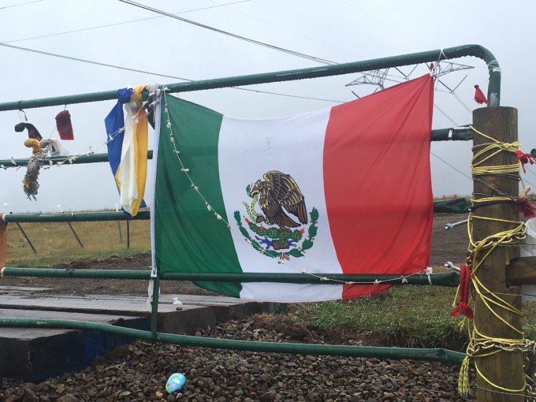 Mexican flag draped across a rusty gate where protesters are working to stop the construction of the Dakota Access Pipeline.