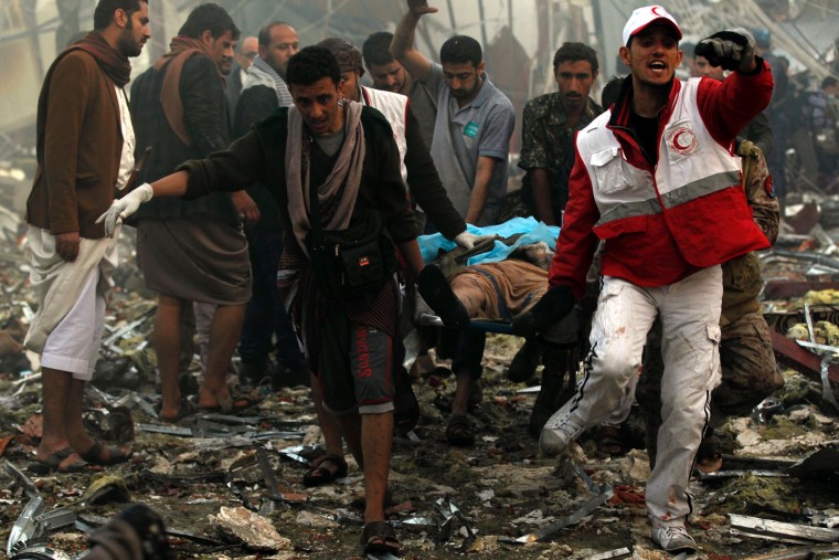 Image: Yemeni rescue workers carry a victim on a stretcher amid the rubble of a the destroyed building.