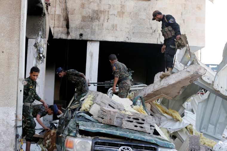 Image: Police troopers search for survivors after what witnesses said was an airstrike by Saudi-led coalition aircraft on mourners at a hall in Sanaa