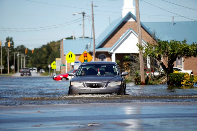 Image: A car navigates a flooded street off Highway 41 in Lumberton