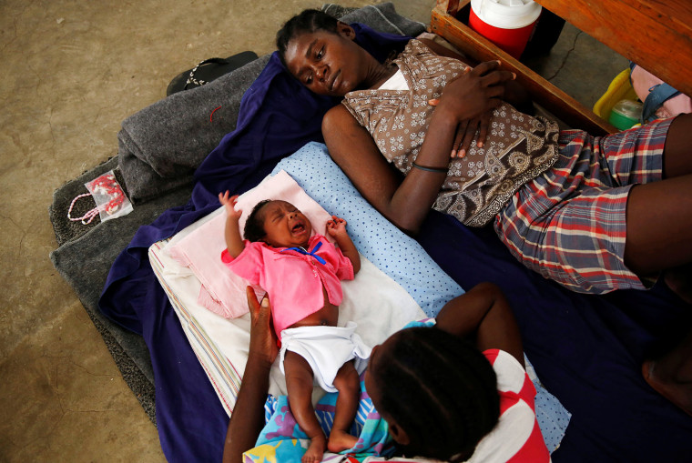 Image: Women and a child rest at a shelter set up at a school after Hurricane Matthew passes in Jeremie
