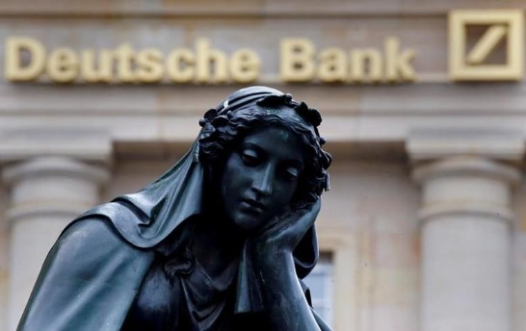 A statue is seen next to the logo of Germany's Deutsche Bank in Frankfurt
