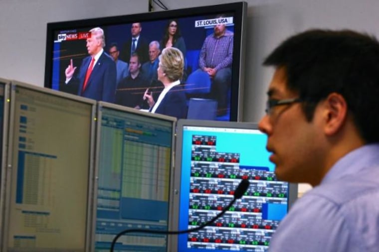 A trader works at his desk as the US presidential town hall debate is shown on television at Citibank's trading floor located in central Sydney, Australia