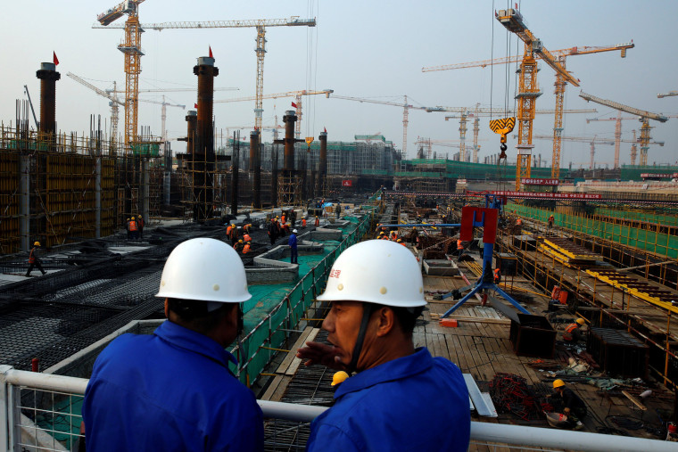 Image: Workers survey the construction site of the terminal for the Beijing New Airport in Beijing