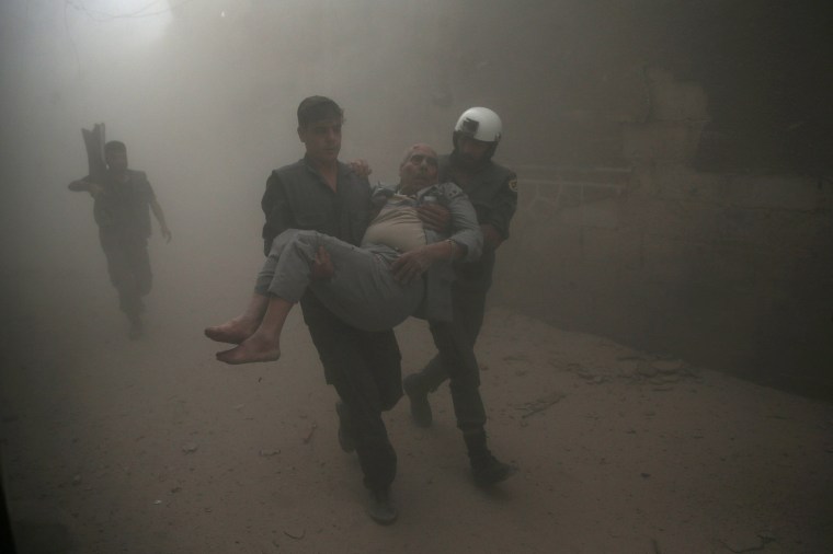 Image: Civil defense members carry an injured man after an air strike in the rebel-held Douma neighbourhood of Damascus