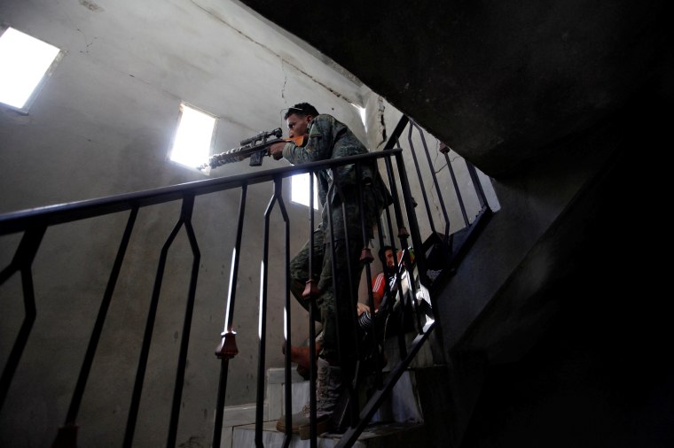 Image: Fighter from Libyan forces allied with the U.N.-backed government aims his weapon through an opening in a wall as forces advance into the last area controlled by Islamic State in Sirte