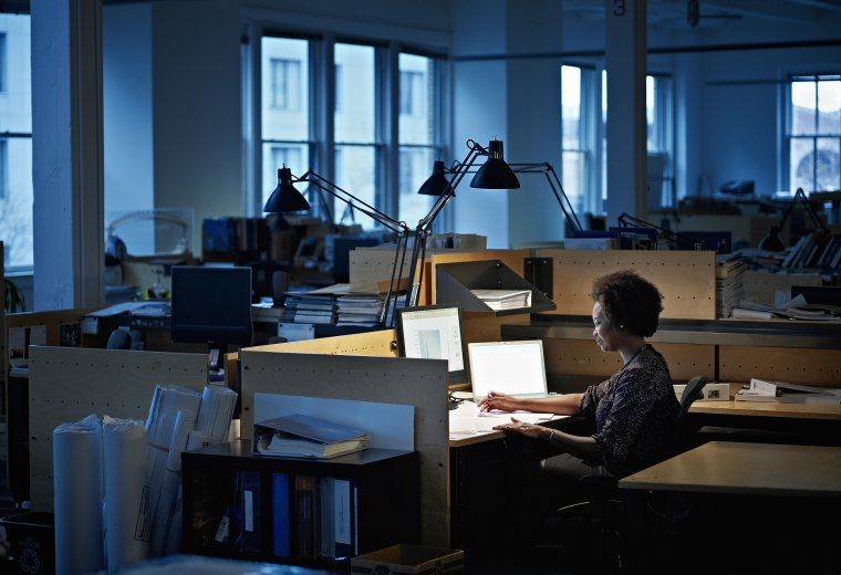 Businesswoman examining documents at desk at night