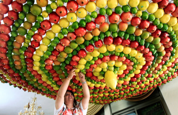 Image: Woman from the Samaritan sect decorates with fruits and vegetables a traditional hut known as a \"sukkah\", which is a ritual hut used during the Jewish holiday of Sukkot, on Mount Gerizim on the outskirts of the West Bank city of Nablus