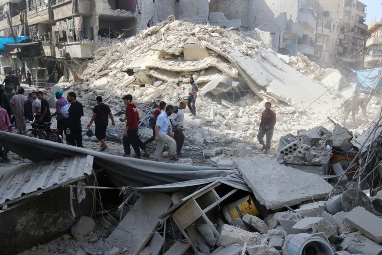 Image: People inspect the damage at a market hit by airstrikes in Aleppo's rebel held al-Fardous district