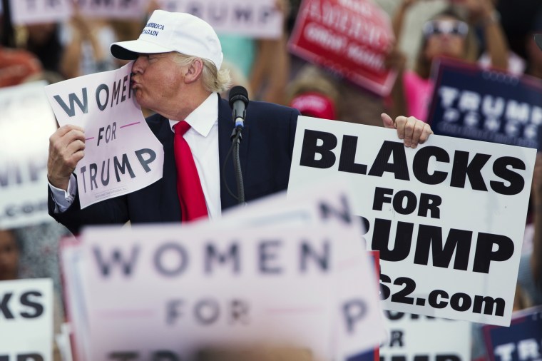 Image: Trump kisses a \"Women for Trump\" sign during a campaign rally