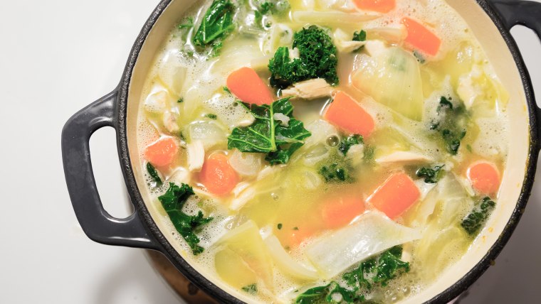 Dutch oven on a stove while cooking chicken noodle soup