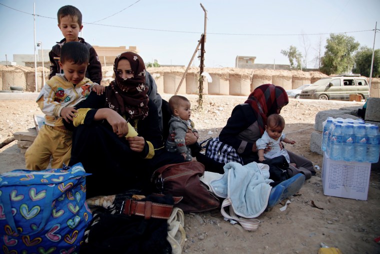 Image: A group of mothers sit with their children at Dibis checkpoint