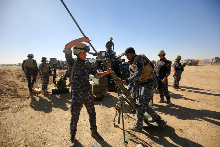 Image: Iraqi policemen clean a weapon at the Qayyarah military base