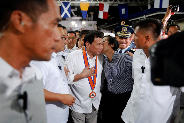 Image: Philippines President Rodrigo Duterte is kissed by a woman in Manila