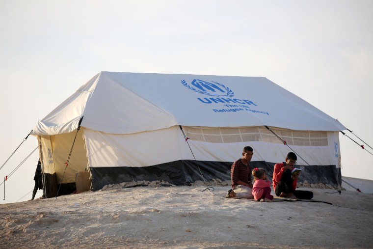 Image: Youth sit outside a UNHCR tent at a refugee camp housing Iraqi families who fled fighting in Mosul