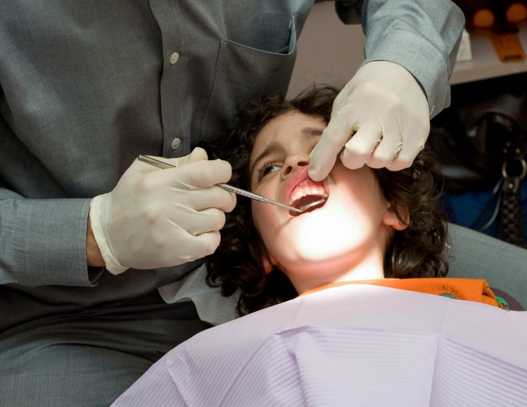 Image: Dentist doctor examines a child's problematic tooth in