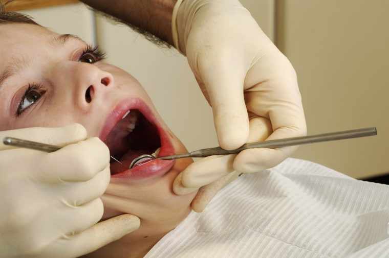 Image: Dentist inspecting boys mouth before treatment