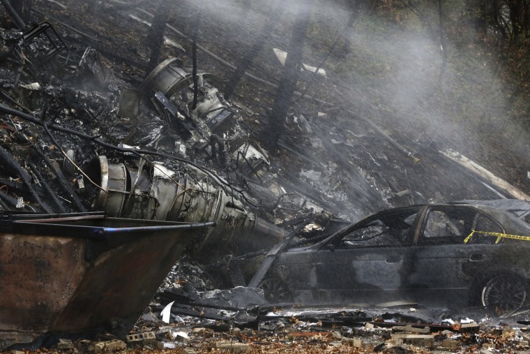 In this Nov. 10, 2015, file photo, a charred car and aircraft debris smolder where a small business jet crashed into an apartment building in Akron, Ohio.