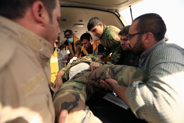 Image: Kurdish Peshmerga fighters carry their injured comrade