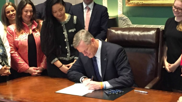 Massachusetts Gov. Charlie Baker signing extending the preservation times of rape kits with Amanda Nguyen to his left.