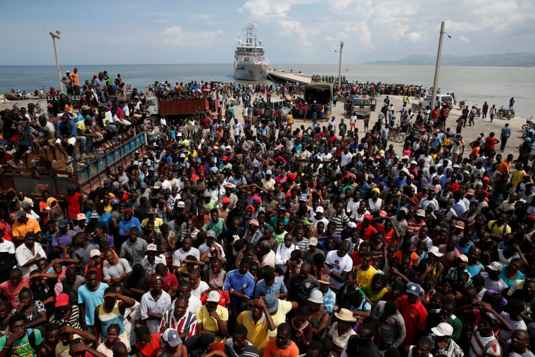 Image: People wait for relief aid to be unloaded from a Dutch navy ship after Hurricane Matthew hit Jeremie