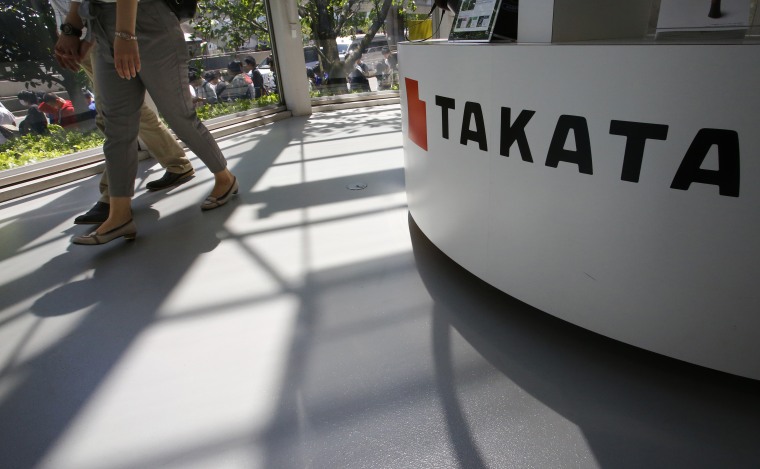 In this May 4, 2016 file photo, visitors walk by a Takata Corp. desk at an automaker's showroom in Tokyo.