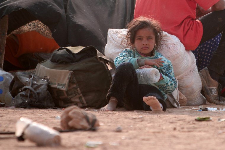 Image: A refugee girl rests, among Iraqi refugees that fled violence in Mosul and internally displaced Syrians whom fled Islamic State controlled areas in Deir al-Zor, near the Iraqi border