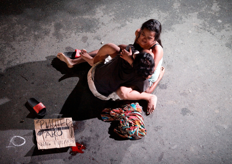 Image: A woman cradles the body of her husband, who was killed on a street by a vigilante group, according to police, in a spate of drug related killings in Pasay city, Metro Manila