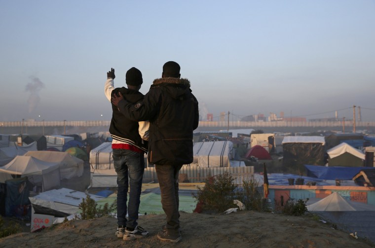 Image: Migrants look at tents and makeshift shelters on the second day of their evacuation and transfer to reception centers during the dismantlement of the \"Jungle\" in Calais