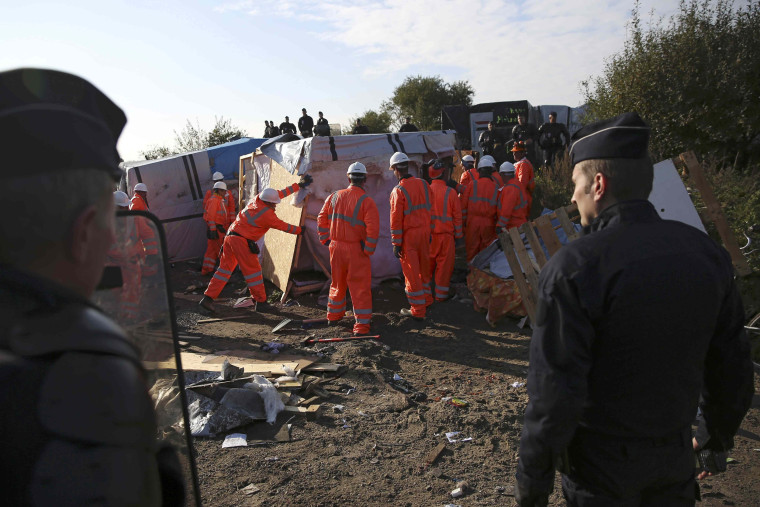 Image: French police watch as workmen tear down a makeshift shelter on the second day the evacuation of migrants and their transfer to reception centers in France, as part of the dismantlement of the camp called the \"Jungle\" in Calais