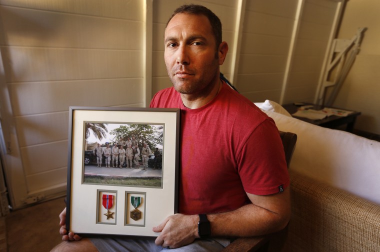 Robert D'Andrea, an Iraq war veteran who served with the U.S. Army and the California National Guard, holds a frame with a photo of his team on his first deployment to Iraq in his home in Los Angeles.