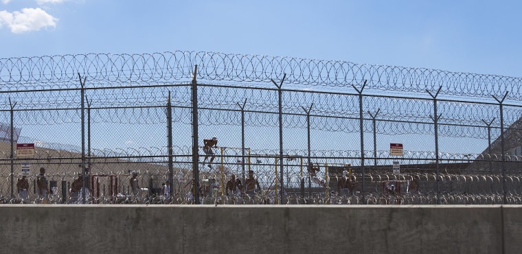 ADELANTO, CA - JULY 7, 2014: Detainees work out in the yard behind double fencing and barbed wire at