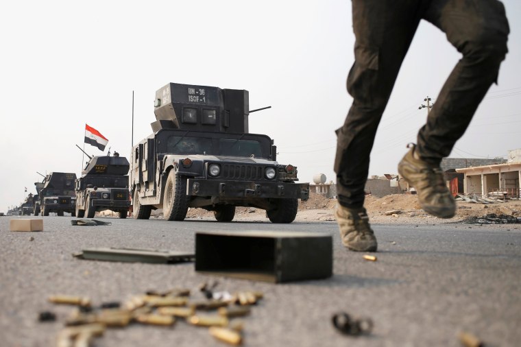 Image: An Iraqi special forces soldier runs as other drive in armoured vehicles on a road near Mosul