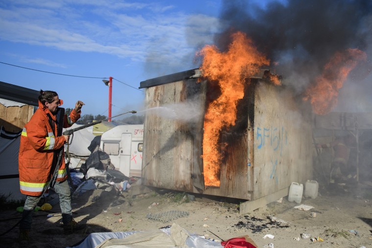 Image: A shelter set alight inside the migrant and refugee camp in Calais, known as the 'Jungle'. Photo by Ben Cawthra/REX/Shutterstock