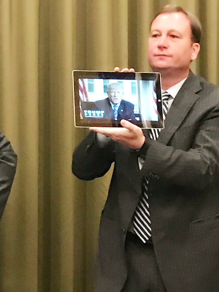 Trump campaign director of coalitions Alan Cobb holding a tablet showing a welcome video featuring Donald Trump at an Asian Pacific American advisory meeting in Nevada ahead of the third presidential debate.