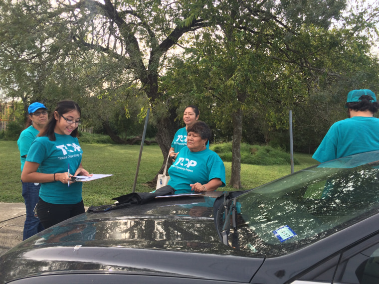 A group of Texas Organizing Project canvassers prepare to knock on doors in South San Antonio. Pictured from left to right are Jessica Azua, at front of car, Rosa Guía, Antonia Flores, Elida Contreras, standing with arm on car, and Miguel Azua, facing away from car.